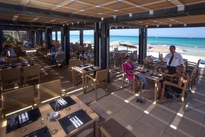 米多恩杰尔巴圣提多海滩酒店的一家餐厅,有坐在海滩桌子旁的人