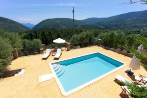 StavrosPilikas Luxury Villas的一座位于庭院内的游泳池,庭院内以群山为背景