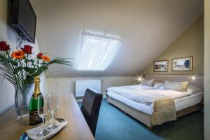 布拉格金牛座酒店的一间卧室配有一张床和一张桌子及一瓶香槟