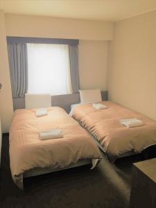 山形市皇冠山形酒店的带窗户的客房内的两张床