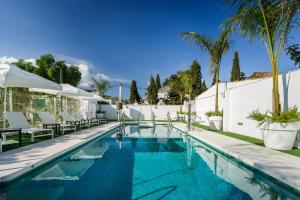 多列毛利诺斯Costa del Sol Torremolinos Hotel的一座带椅子和棕榈树的游泳池,毗邻一座建筑