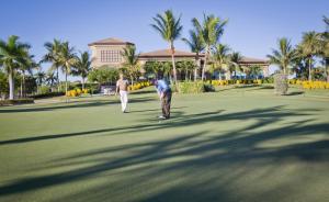 那不勒斯雷里度假村格里林克高尔夫别墅的两个人在棕榈树高尔夫球场上散步