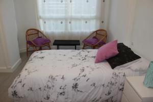阿利坎特Apartamento Luceros的一间卧室配有一张床、两把椅子和一个窗户