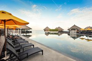 雪邦Avani Sepang Goldcoast Resort的度假酒店的游泳池配有椅子和遮阳伞