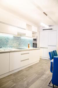 布达佩斯蓝色奢华公寓的厨房配有白色橱柜和蓝色椅子