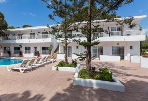 米乔尔海滩Hostal Es Pi - Emar Hotels的一座带躺椅和游泳池的大型白色建筑