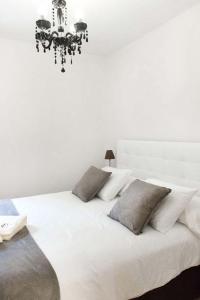 维多利亚-加斯特伊兹Apartamento Vitoria的白色的床、白色枕头和吊灯