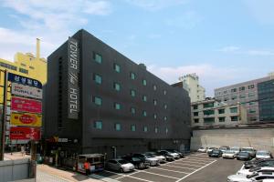 釜山塔山酒店的一座黑色的大建筑,停车场有汽车停放