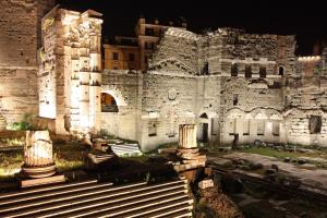 罗马马里迪当代套房酒店 的一座大型石头建筑,晚上在前面有台阶