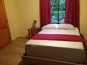 曼萨尼约Suites Chile Verde的一间卧室配有一张带红色窗帘的床和一扇窗户