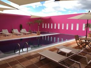 普埃布拉卡萨雷纳精品酒店的粉红色墙壁旁的游泳池,配有桌椅
