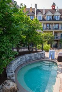 蒙特朗布朗旅行者酒店的一座带石墙的庭院内的游泳池