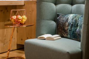 圣安东阿尔贝格"Quality Hosts Arlberg" Hotel zur Pfeffermühle的一张沙发,上面有一本开放式的书和一碗苹果