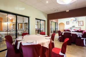Humilladero拉塞内西拉营地酒店的用餐室配有桌子和红色椅子