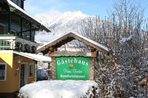 格洛博明Gästehaus Fuchs的建筑物前雪中的标志