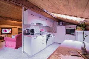 利维尼奥Mansardalpina的配有白色家电和粉红色椅子的厨房