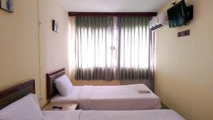 董里โรงแรมวัฒนาตรัง的酒店客房设有两张床和窗户。