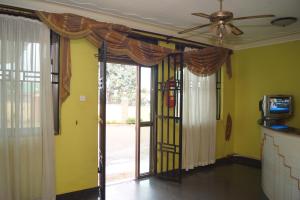 坎帕拉Durban Motel Najjanankumbi Kampala的客厅配有吊扇和滑动玻璃门。