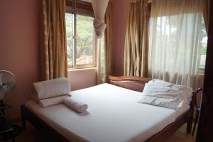 坎帕拉Durban Motel Najjanankumbi Kampala的一间卧室配有一张带窗户和枕头的床