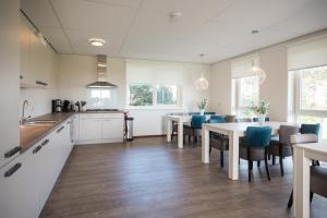 比伦De Oranjerie的厨房配有白色橱柜、桌子和蓝色椅子