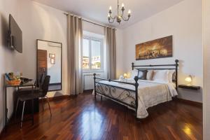 罗马小罗马套房酒店的一间卧室配有一张床、一张书桌和一个窗户。