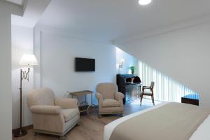 桑坦德Suite Home Sardinero的一间设有两把椅子、一台电视和楼梯的房间