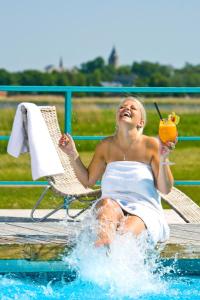 哈普萨卢弗拉马雷海水浴场Spa酒店的坐在游泳池里喝一杯的女人