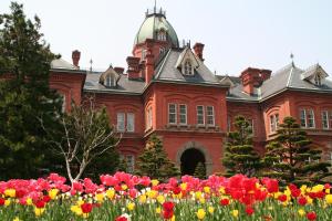 札幌札幌站前巢酒店的一座红色的大建筑,前面有鲜花