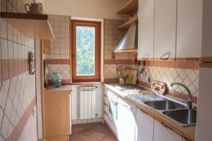 特雷维尼亚诺罗马诺Gli Ulivi的厨房配有白色橱柜、水槽和窗户。