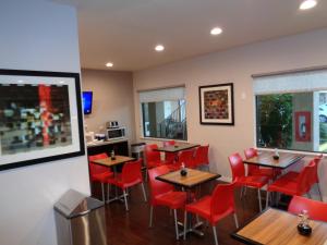 休斯顿Grand Villa Inn Galleria的餐厅设有木桌和红色椅子