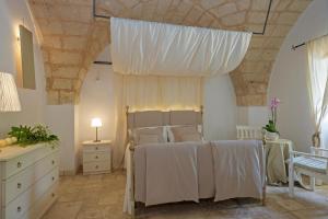 圣维托诺曼Masseria Pagliamonte的一间卧室配有一张带白色床单和天花板的床。
