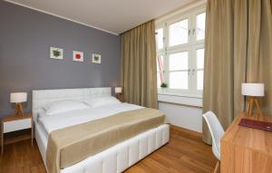 布拉格花苑酒店的卧室配有白色的床、书桌和窗户。