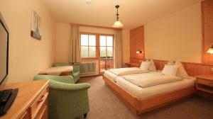 拉姆绍达赫斯坦阿尔彭佩乐旅馆的一间卧室配有一张床、一张沙发和一把椅子
