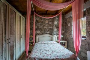 波利兹罗松Naiades Village的卧室配有一张粉红色窗帘的床