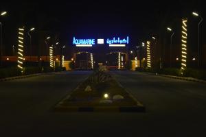 Al Nuwaiseeb海蓝宝石科威特度假村（仅限家庭）的一条空的街道,晚上有 ⁇ 虹灯标志的建筑