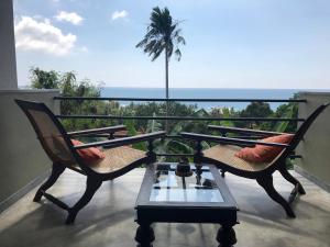 乌纳瓦图纳劳拉之家酒店的阳台配有两把椅子和一张桌子,还种植了棕榈树