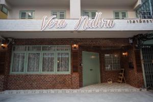 曼谷Vera Nidhra - Self check-in after 7pm的砖砌的建筑,上面有读取邻居的标志