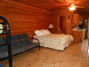 布里奇波特Bay Landing Camping Resort Deluxe Cabin 29的小屋内一间卧室配有一张床和一张沙发