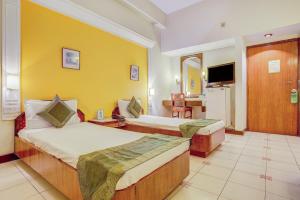 德拉敦Hotel Ajanta Continental的酒店客房设有两张床和电视。