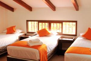 San Ignacio de VelascoHotel Tierra Linda的一间设有3张床的客房,配有橙色和白色的床单