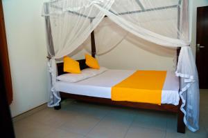 坦加拉4 S Villa的一间卧室配有天蓬床,提供黄色和橙色枕头