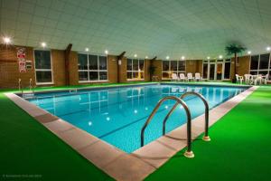 诺里奇温瑟姆山谷高尔夫乡村俱乐部酒店的一座绿色建筑中的大型游泳池