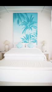 龙目岛库塔和谐公寓的卧室配有白色的床和棕榈树壁画