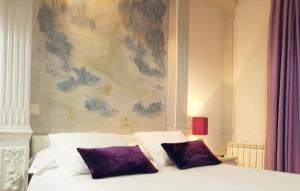马德里特拉安旅馆的画前床带两个紫色枕头