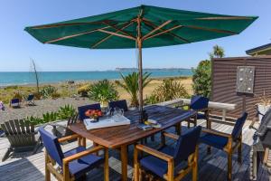 纳皮尔绝对海滨住宿加早餐旅馆的海滩上一张木桌和椅子及遮阳伞