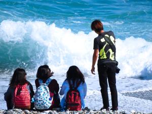 盐寮海元素178民宿的一群坐在海滩上的人,看着大海