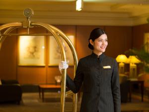 神户神户湾喜来登酒店&塔楼的站在酒店大堂的一位妇女,她拿着一根杆