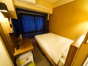 东京池袋站北口乐活超级酒店的小房间设有一张床和一张桌子