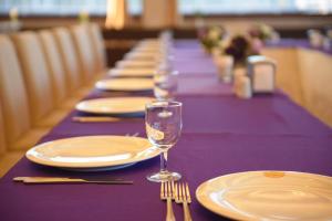 萨姆松My House Hotel的长紫色的桌子,带盘子和酒杯