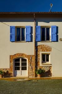 诺维利古雷德梅特拉农场住宿加早餐旅馆的白色的房子,设有蓝色百叶窗和两扇窗户